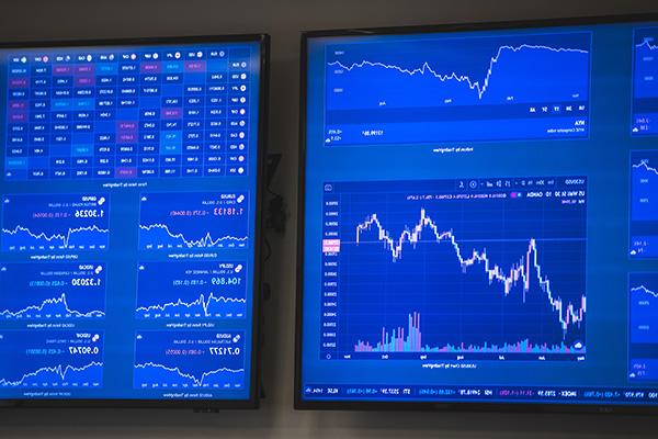 two monitors displaying stock market 和 financial graphs