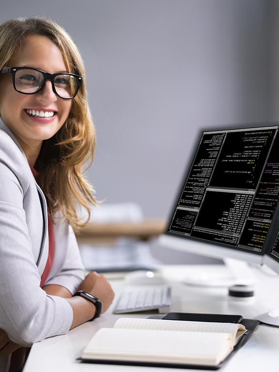Female programmer typing codes to new software on computer while sitting at her workplace at office